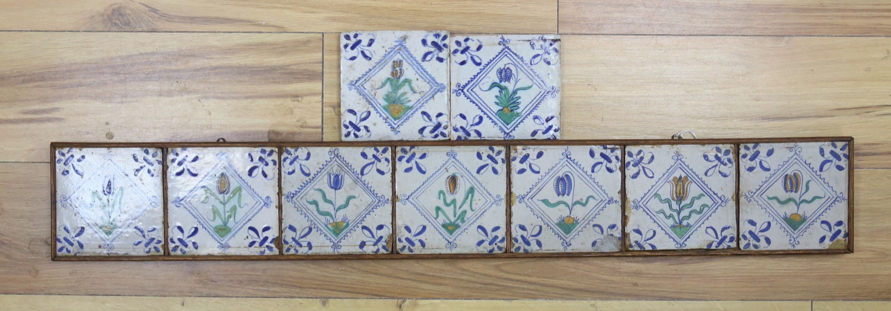 Seven 17th century Dutch Delft tiles, polychrome-decorated with tulips and having fleur-de-lys corners (framed 95cm)